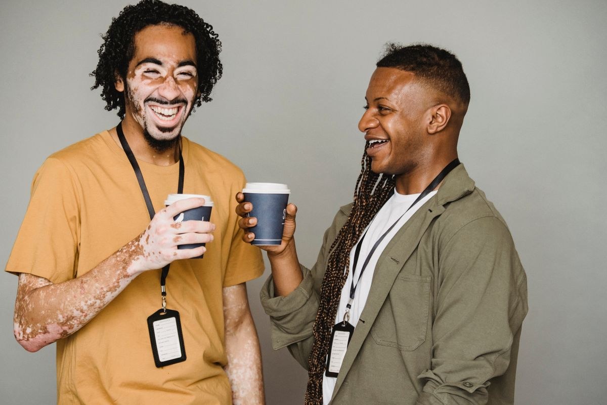 Two adults laughing and talking together over coffee.