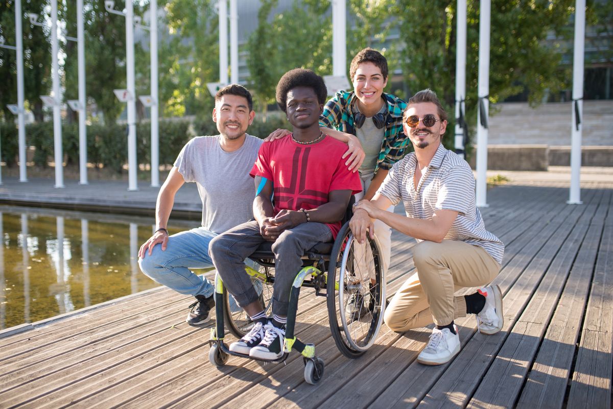 Four friends spending time together outdoors, including a friend who uses a wheelchair.